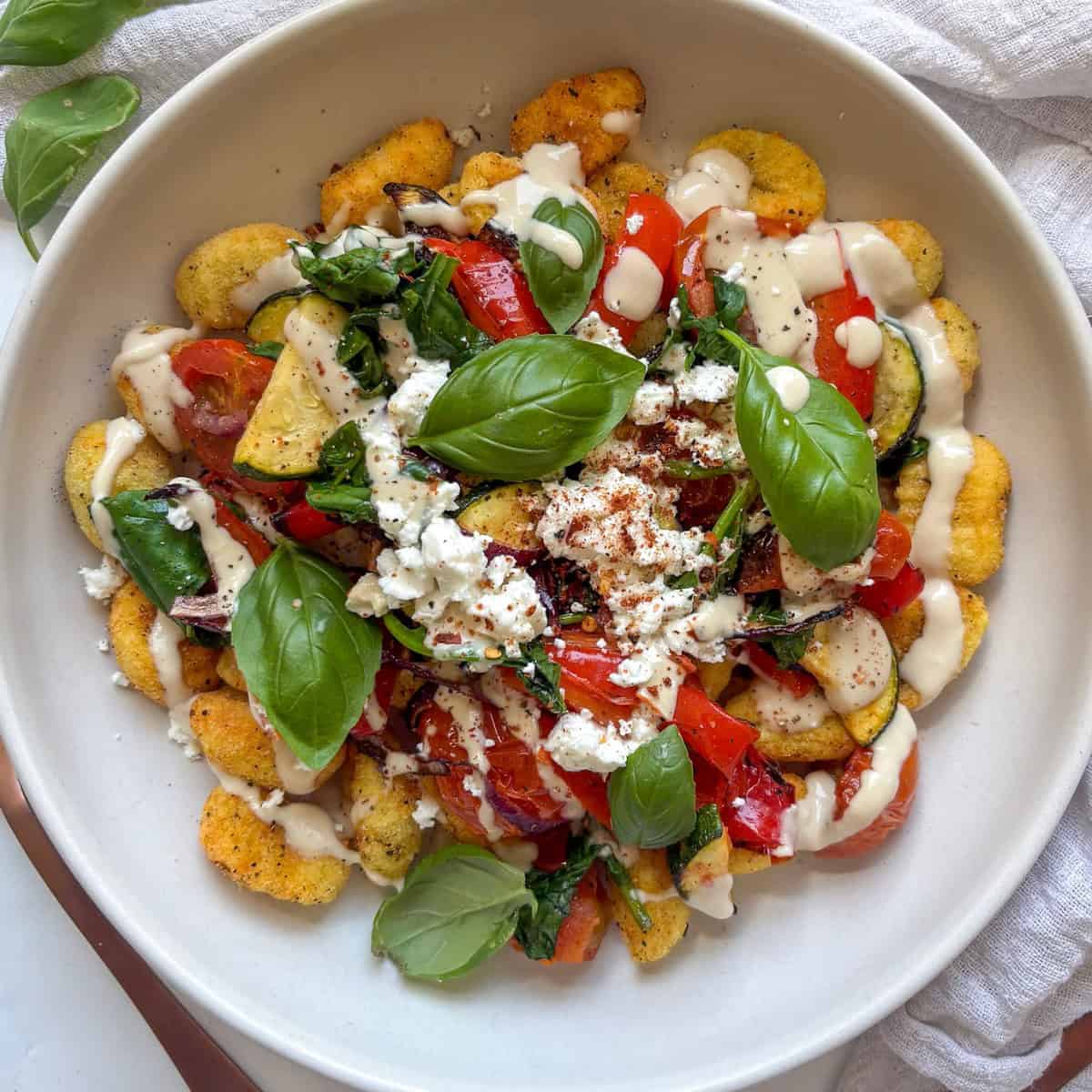 baked gnocchi with roasted vegetables, crumbled feta, and a lemony tahini dressing