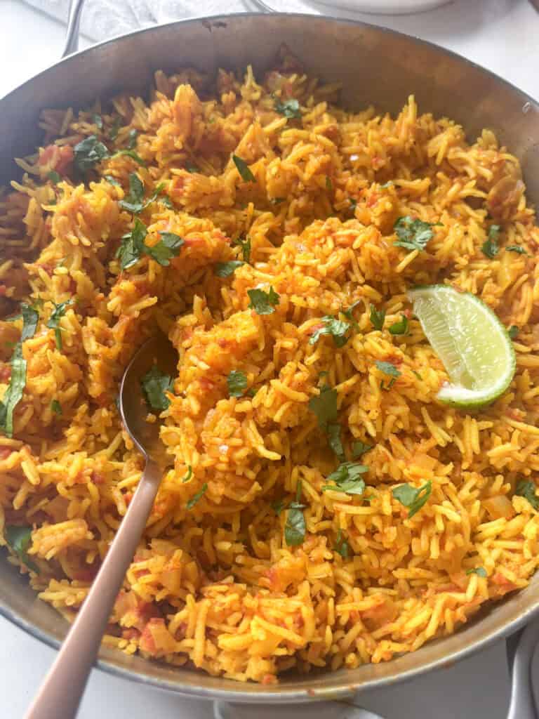 fluffy spicy rice in a pan topped with fresh herbs