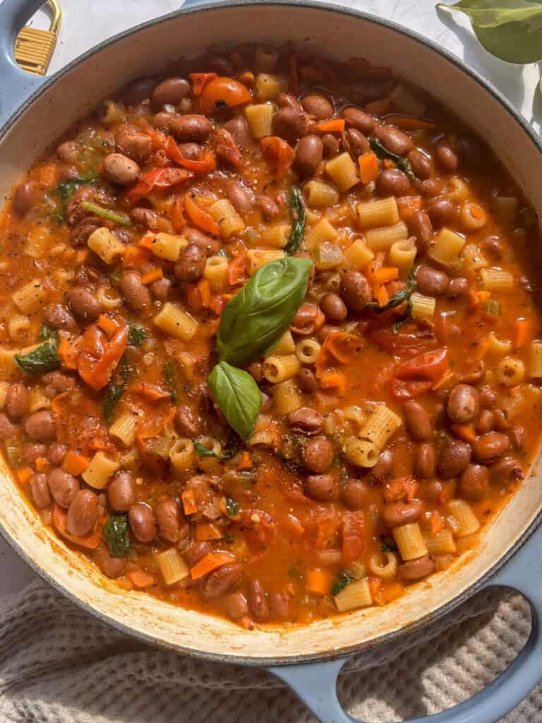 a casserole dish of pasta e fagioli topped with black pepper and fresh basil