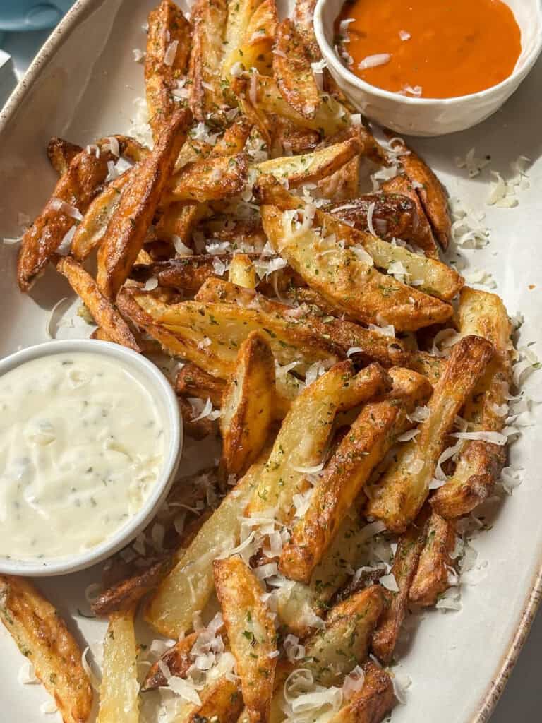 crispy garlic parmesan fries on a platter with a dip