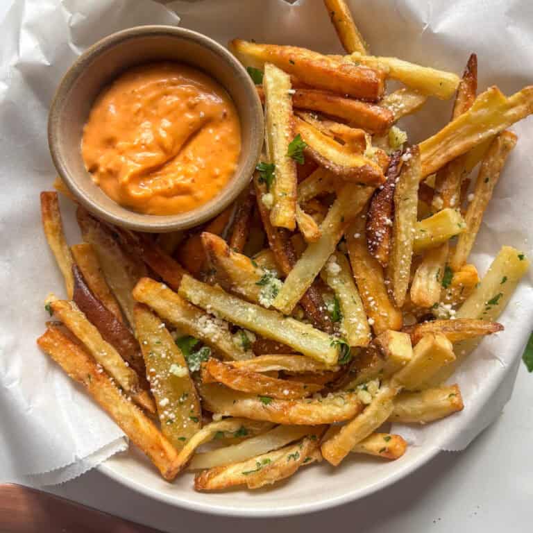 crispy garlic parmesan fries in a bowl with a chipotle mayo sauce