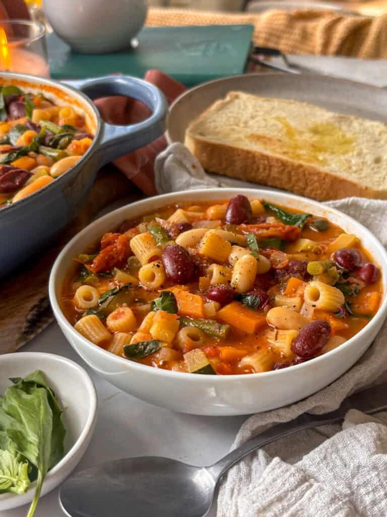 a side on view of the hearty minestrone soup in a white bowl