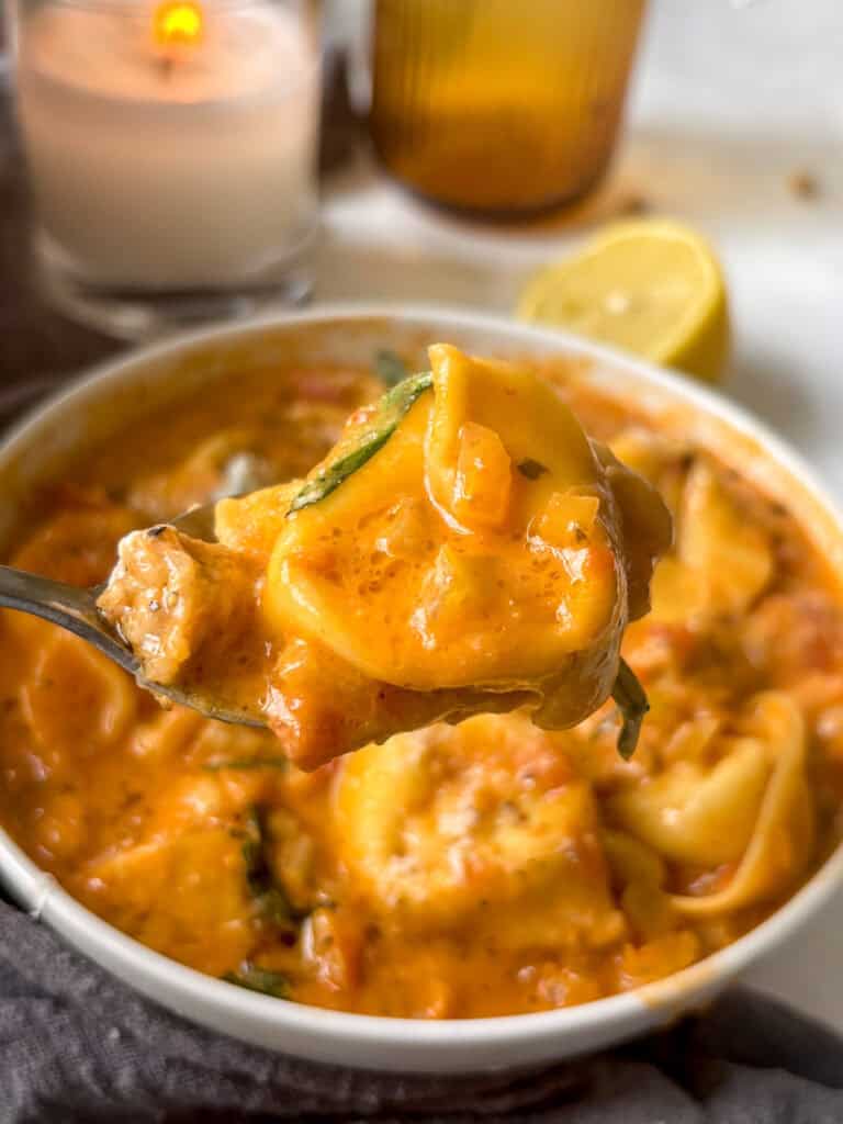 a spoonful of creamy tortellini soup with tortellin and sausage and the creamy sauce