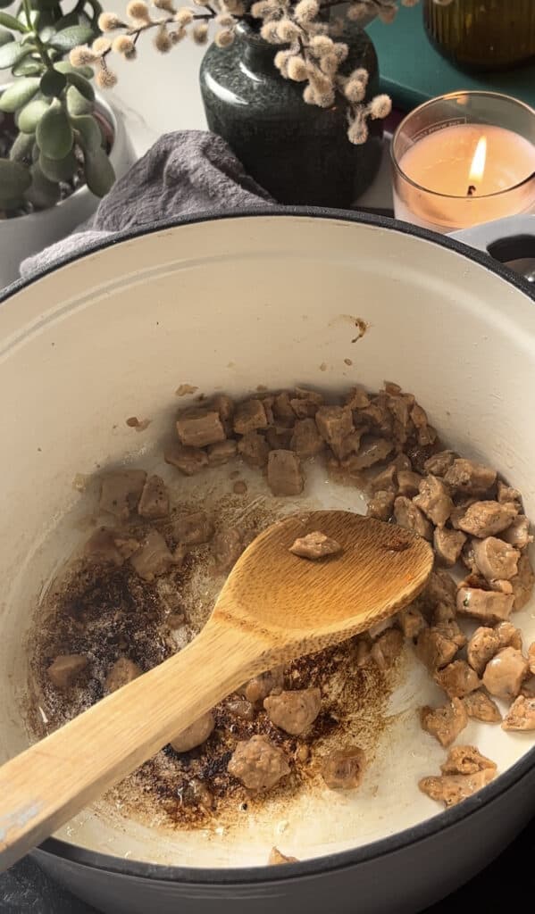 sausages frying in a casserole pan
