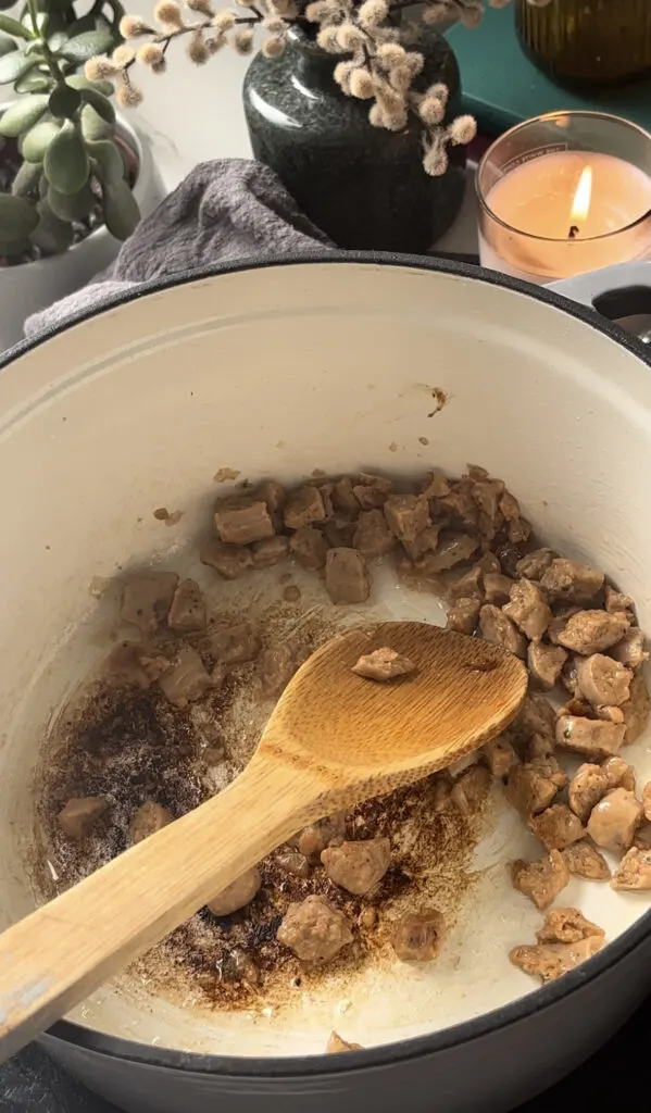 sausages frying in a casserole pan