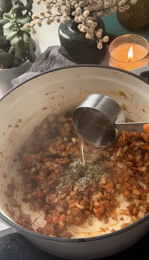 seasonings, tomato paste, and white wine being added to the pan