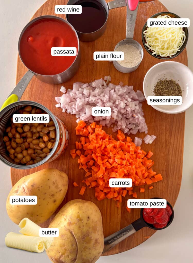 ingredients shot of the ingredients for vegetarian shepherd's pie: green lentils, onion, carrots, garlic, seasonings, flour, passata, tomato paste, potatoes, butter, and grated cheese. The butter and cheese images were added digitally to showcase every ingredient needed