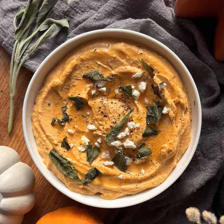 a bowl of pumpkin whipped feta, topped with crispy sage and more crumbled feta