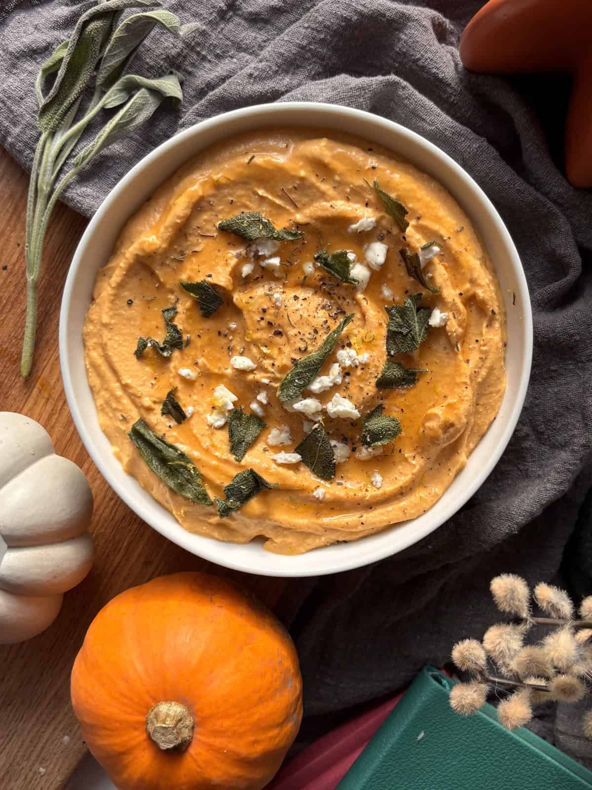 a bowl of pumpkin whipped feta, topped with crispy sage and more crumbled feta