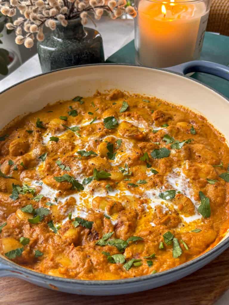 the pan with the butter bean curry drizzled with coconut milk and parsley