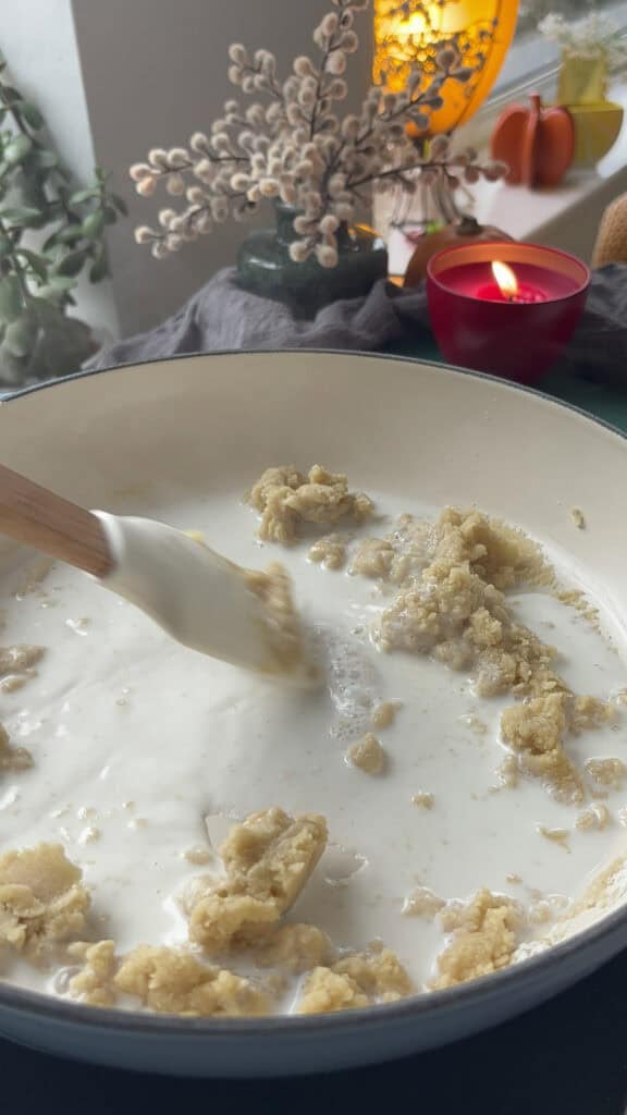 milk being whisked into the flour and butter mixture in the pan