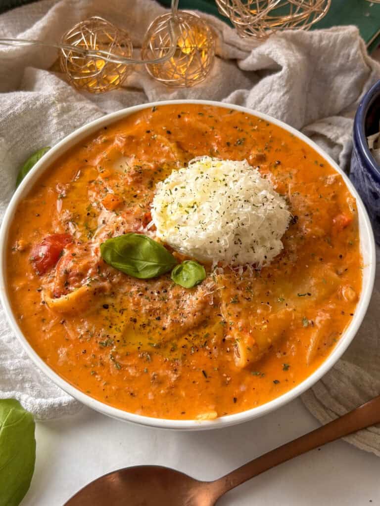 a bowl of vegetarian lasagna soup topped with ricotta, basol, and pecorno