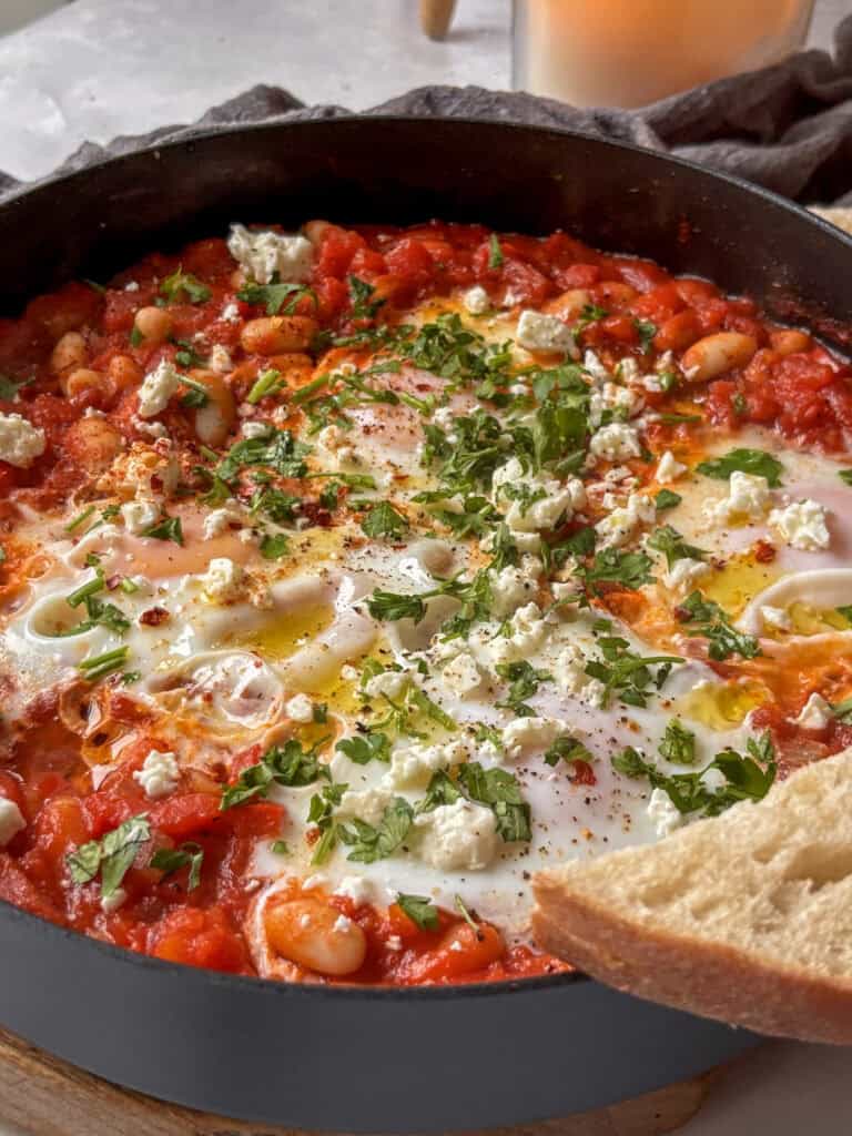 a skillet of white bean shakshuka topped with feta and parsley