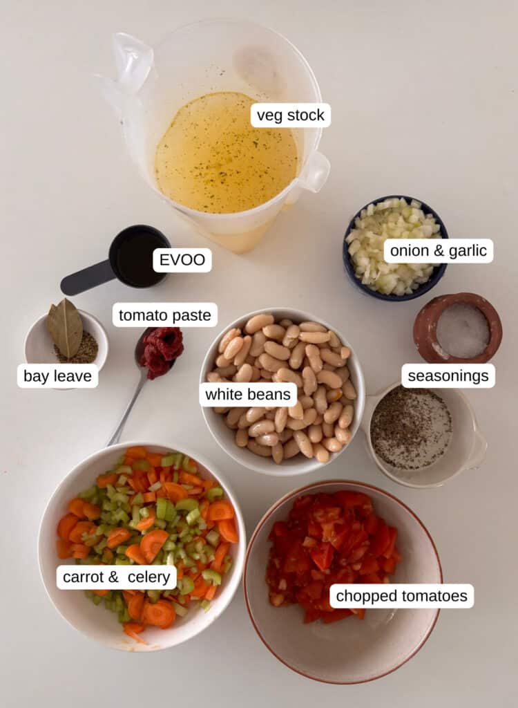 fasolada - greek bean soup - ingredients list: onion, garlic, celery, carrot, white beans, olive oil, tomato paste, bay leaves, oregano, chopped tomatoes