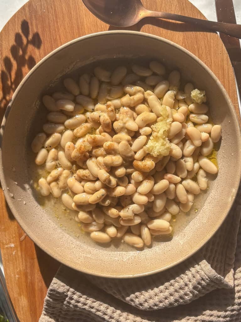 all the components for the white bean dip: white beans, garlic, olive oil, cumin, tahini, salt, pepper