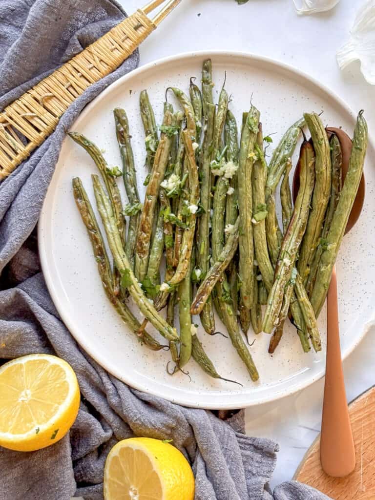 roasted green beans on a plate with garlic and parsley topping
