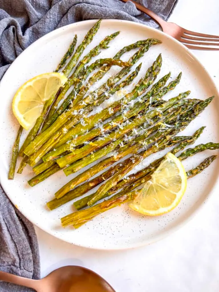 a plate of air fryer asparagus topped with lemon slices and Pecorino cheese
