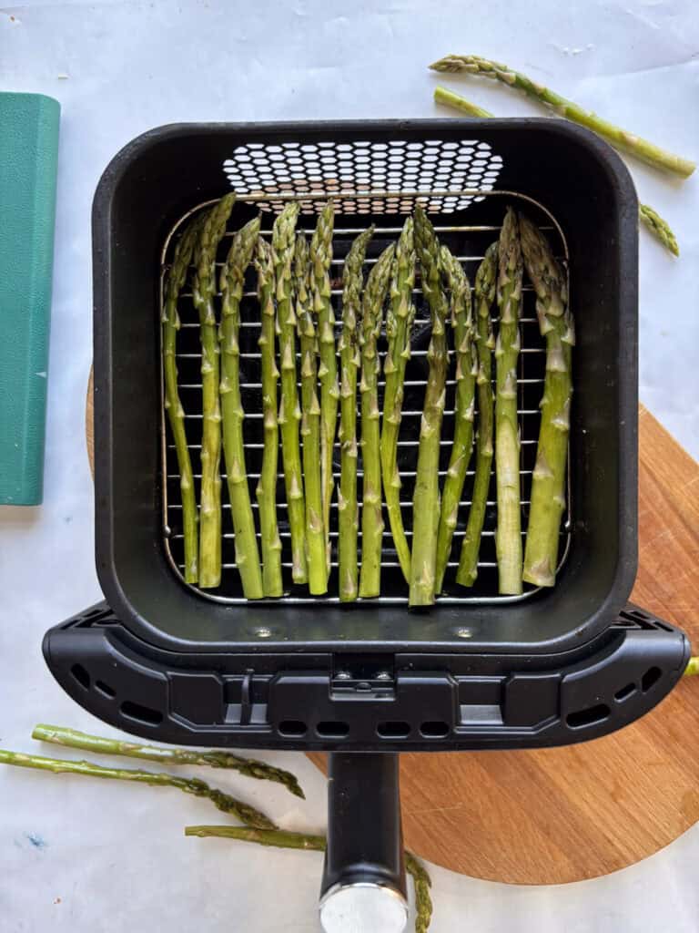 asparagus lined up on air fryer basket