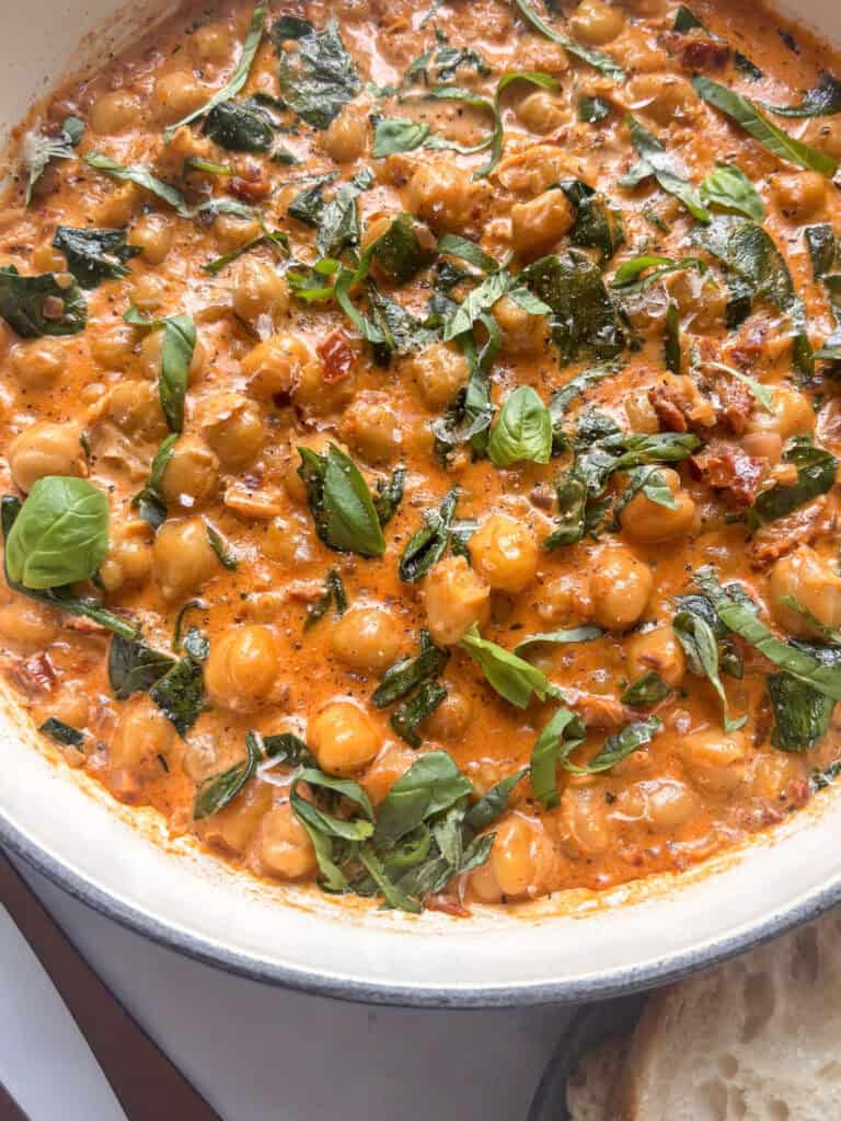 a close up image of creamy Marry Me Chickpeas with spinach, basil, and sun-dried tomatoes