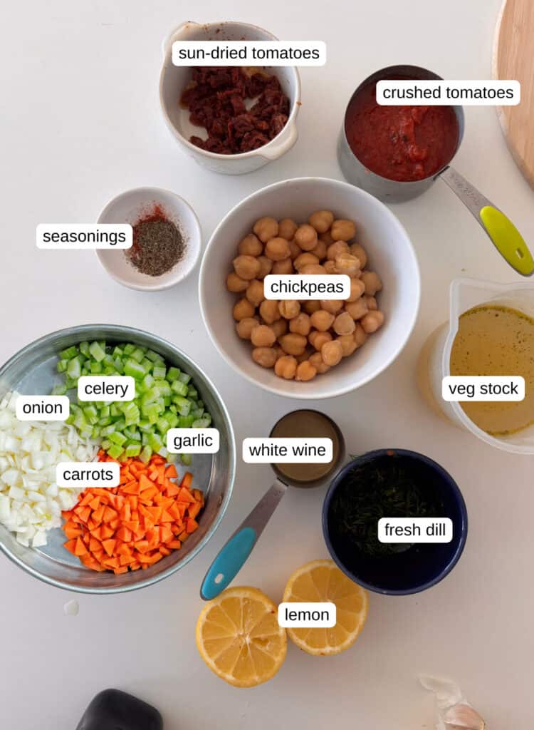 ingredients shot for chickpea soup: onion, celery, carrot, garlic, chickpeas, white wine, herbs, crushed tomatoes, sun-dried tomatoes, fresh dill, lemon