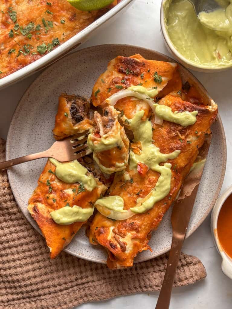 a plate of black bean enchiladas topped with creamy avocado crema