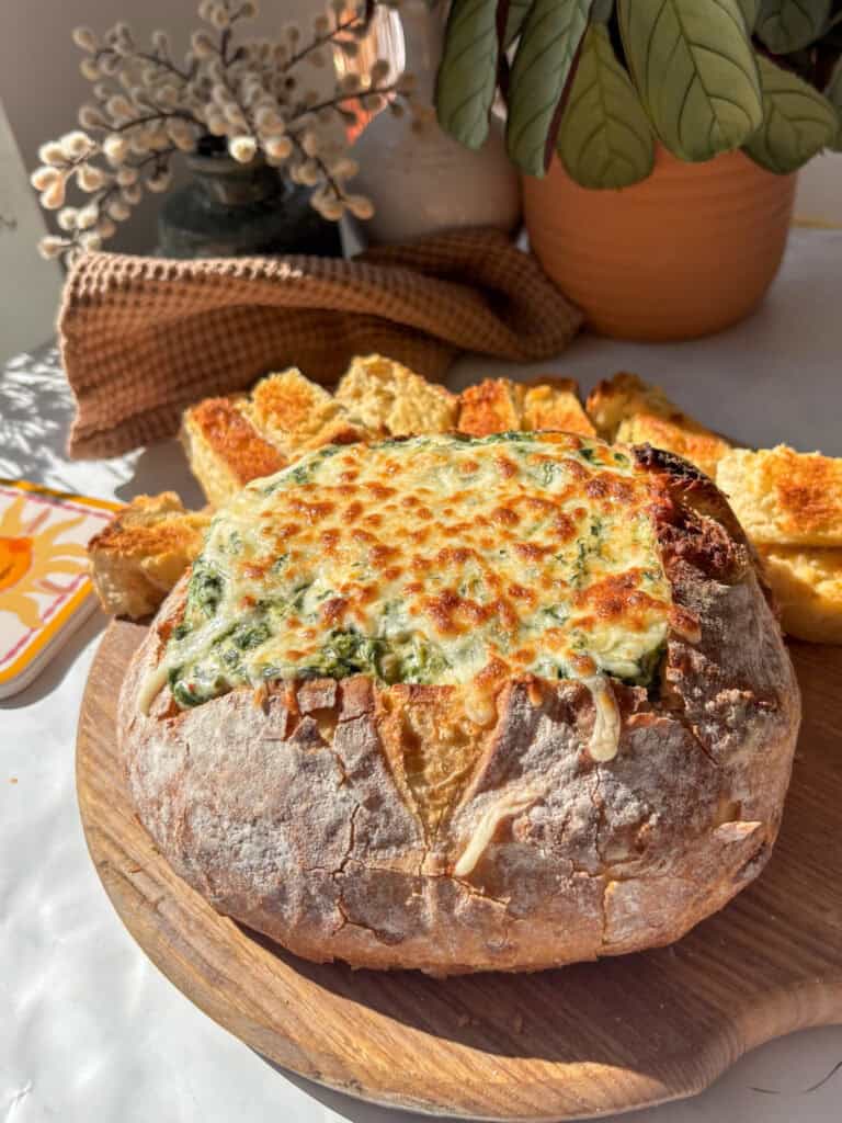 hot and cheesy spinach dip recipe served in a bread bowl with toasted bread on the side