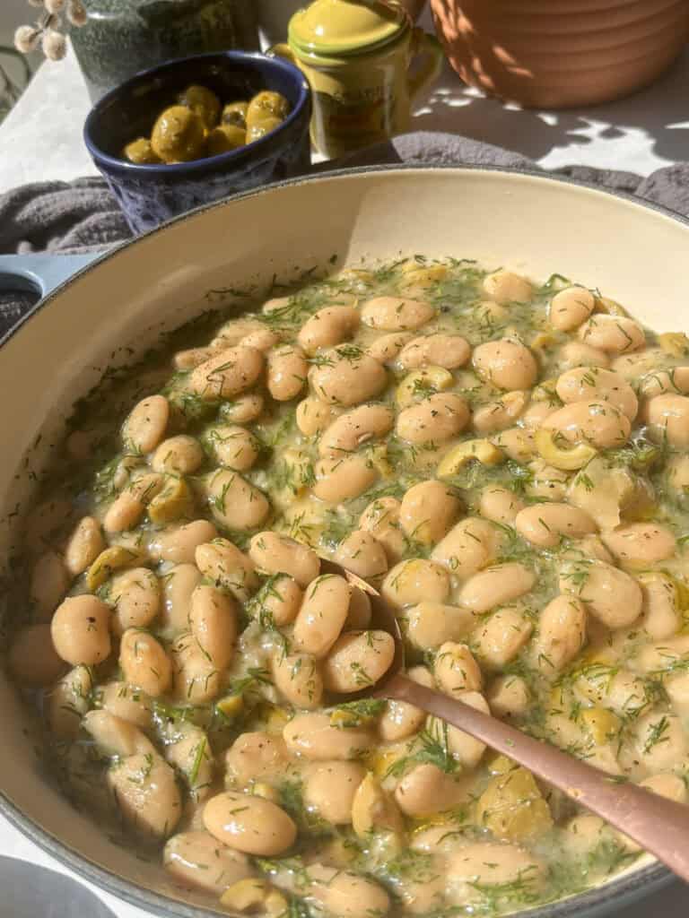 a casserole pan of lemon and dill butter beans with green olives