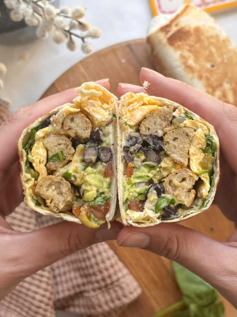 breakfast burritos stacked up on each other, cut in half to show the crossection of vegetartian sausages, egg, black beans, spinach, avocado etc
