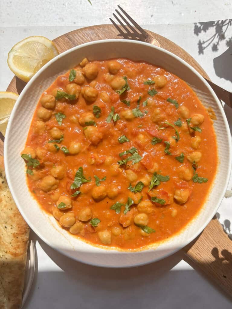 creamy coconut chickpea curry in a white bowl topped with chopped cilantro
