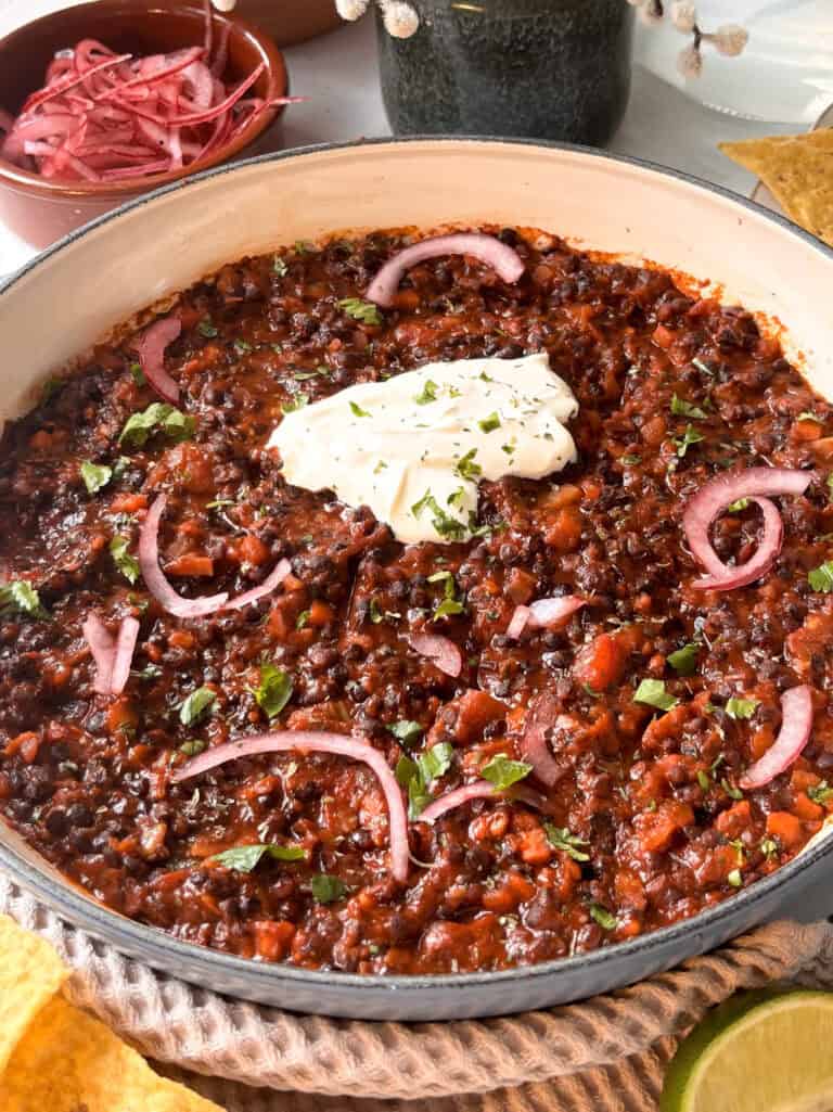 lentil taco meat recipe in a pan topped with sour cream and pickled red onions