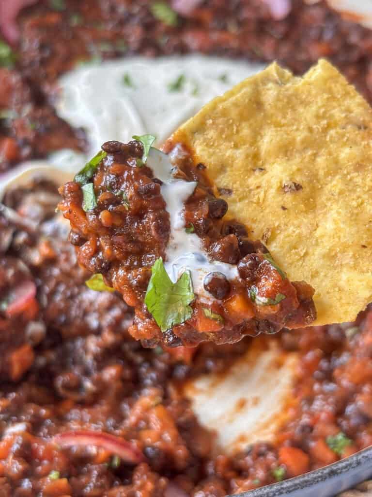 a tortilla chip loaded with lentil taco meat and sour cream