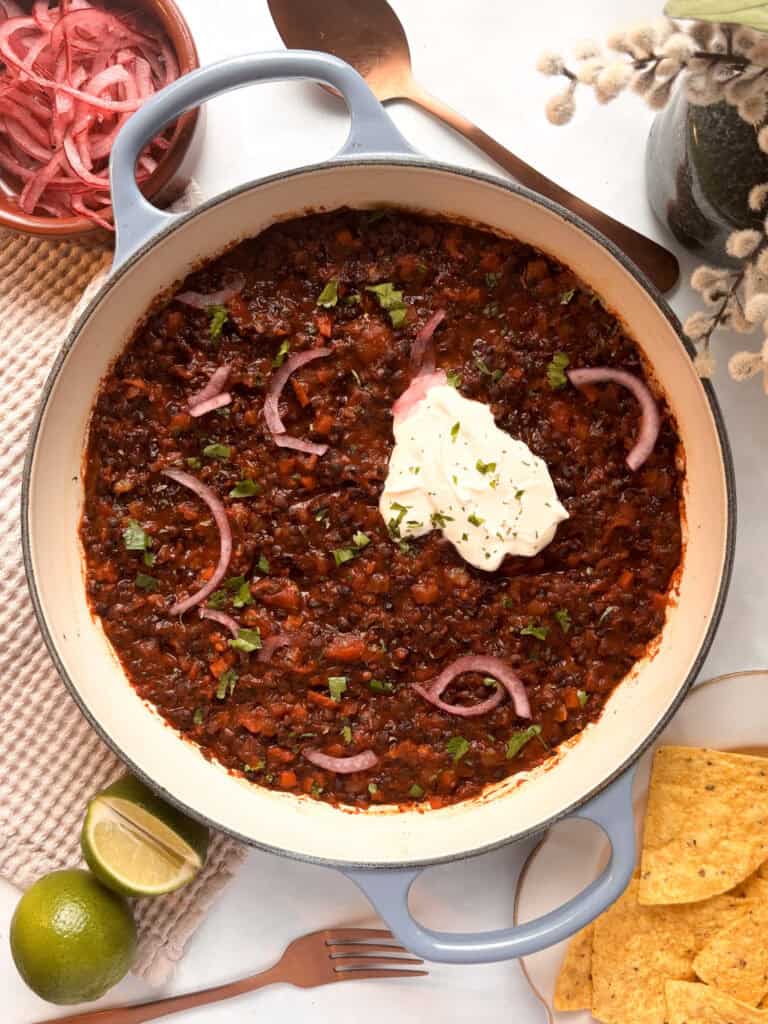 a pan of lentil taco meat - smoky chipotle lentils topped with sour cream and pickled red onions