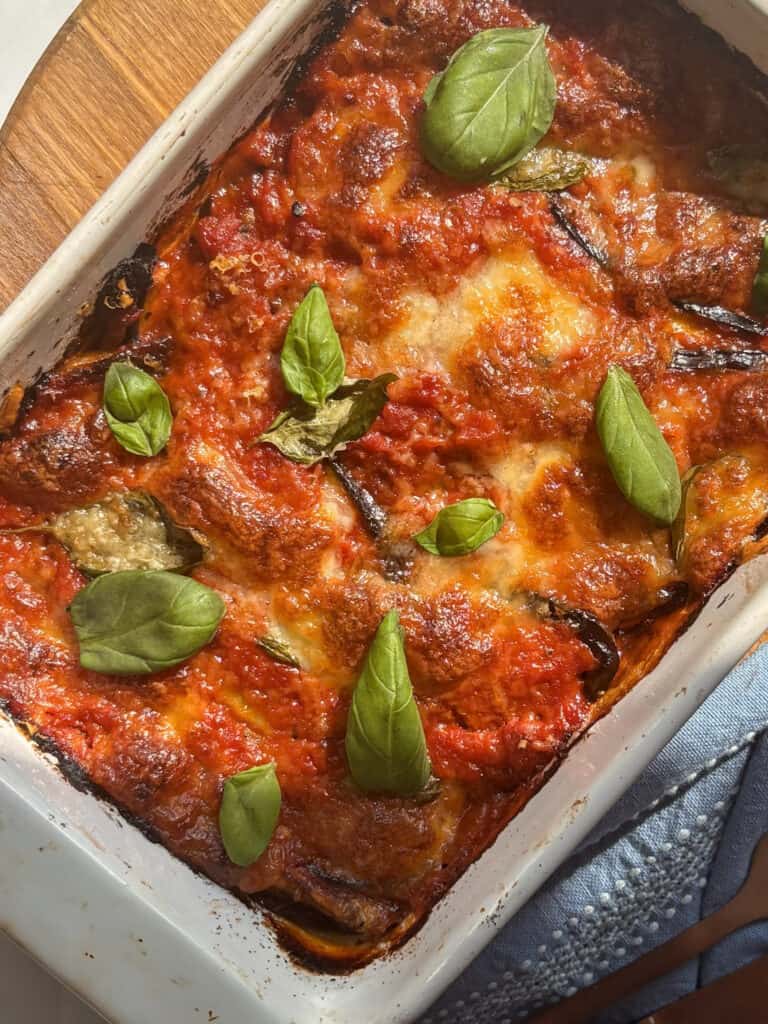 Eggplant parmigiana in a baking dish topped with fresh basil