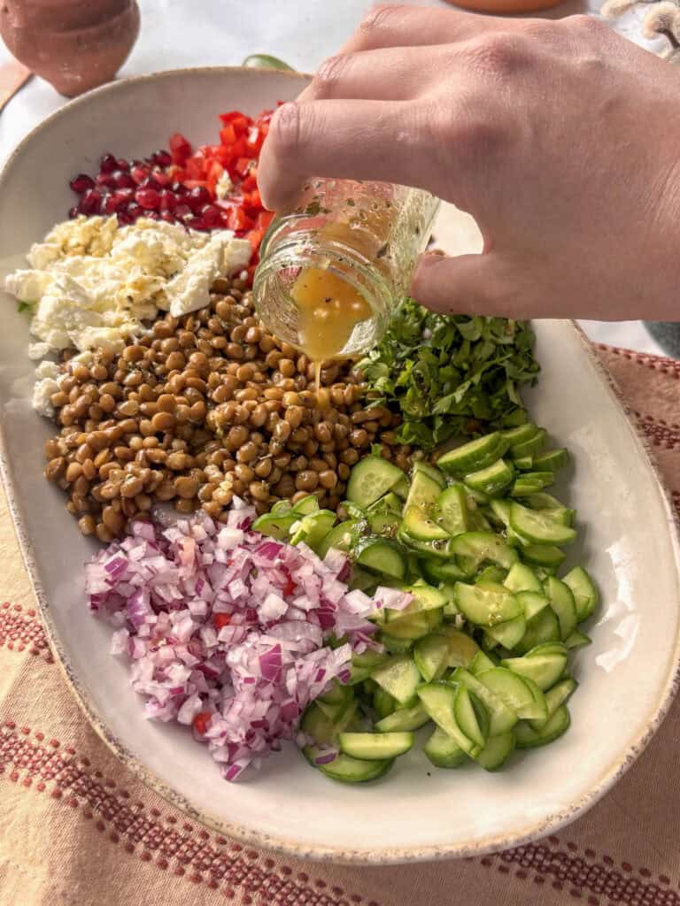 the simple lentil salad on a serving plate with a vinegrette dressing being bored over it