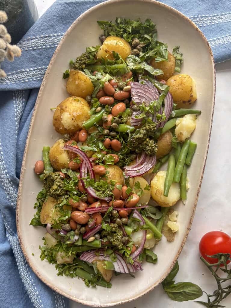 potato and green bean salad with all the ingredients (excluding the dressing and eggs) added to the plate
