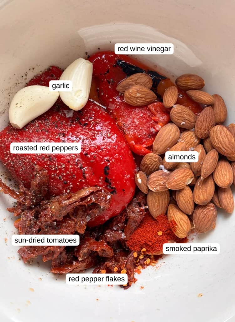 ingredients required for a romesco sauce: red wine vinegar, garlic, almonds, roasted red peppers, sun-dried tomatoes, paprika, red pepper flakes, olive oil
