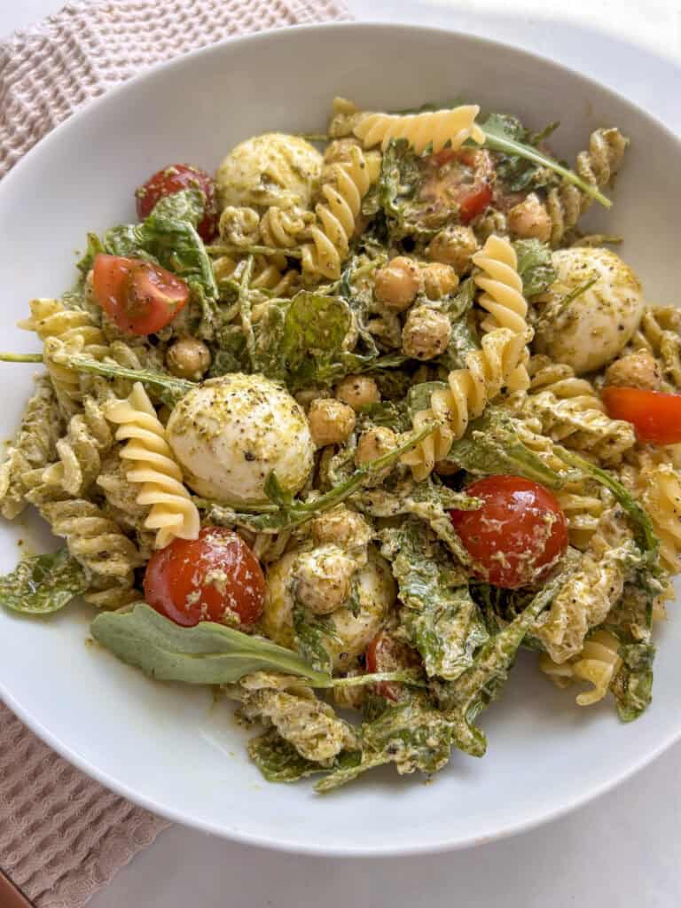 close up of pesto pasta salad in a white bowl