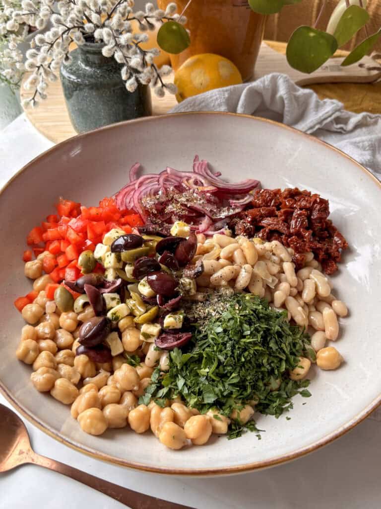 a close up shot of the dense bean salad in a large salad bowl, before the salad has been mixed