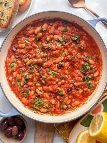 a pan of white bean puttanesca with olives, capers, and white beans