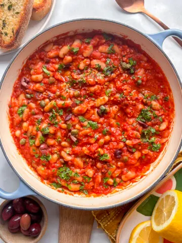 a pan of white bean puttanesca with olives, capers, and white beans