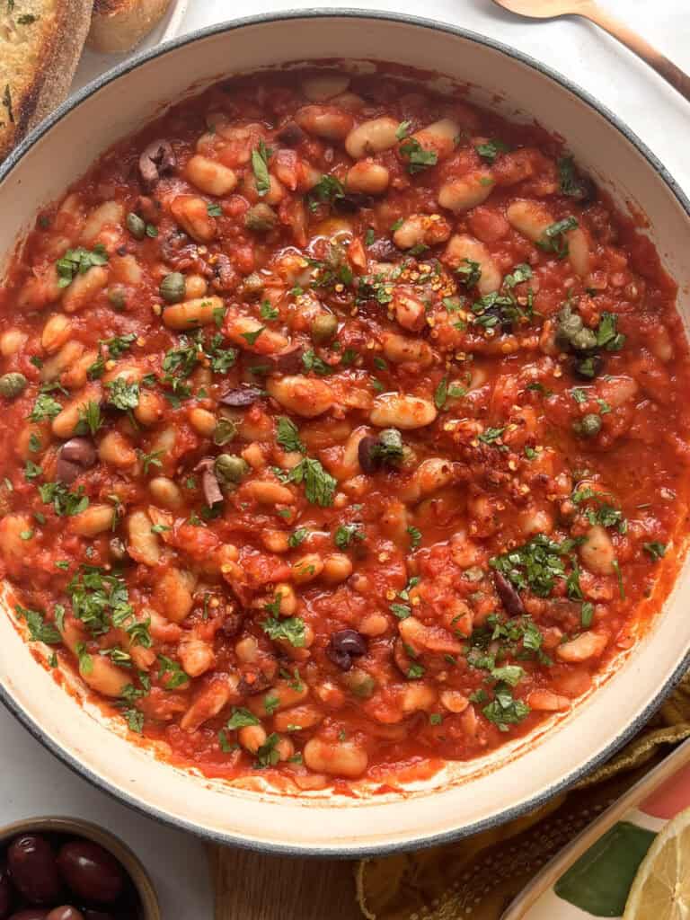 a tomato white bean puttanesca topped with chili flakes and parsley