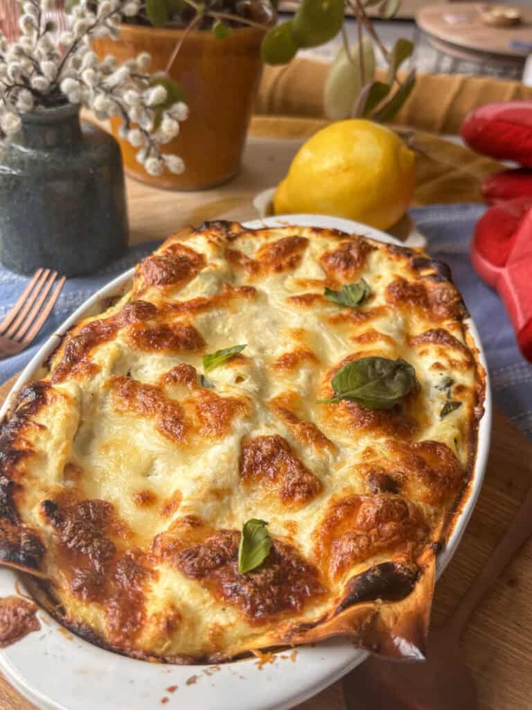 zucchini lasagna in a white baking dish with fresh basil leaves on top