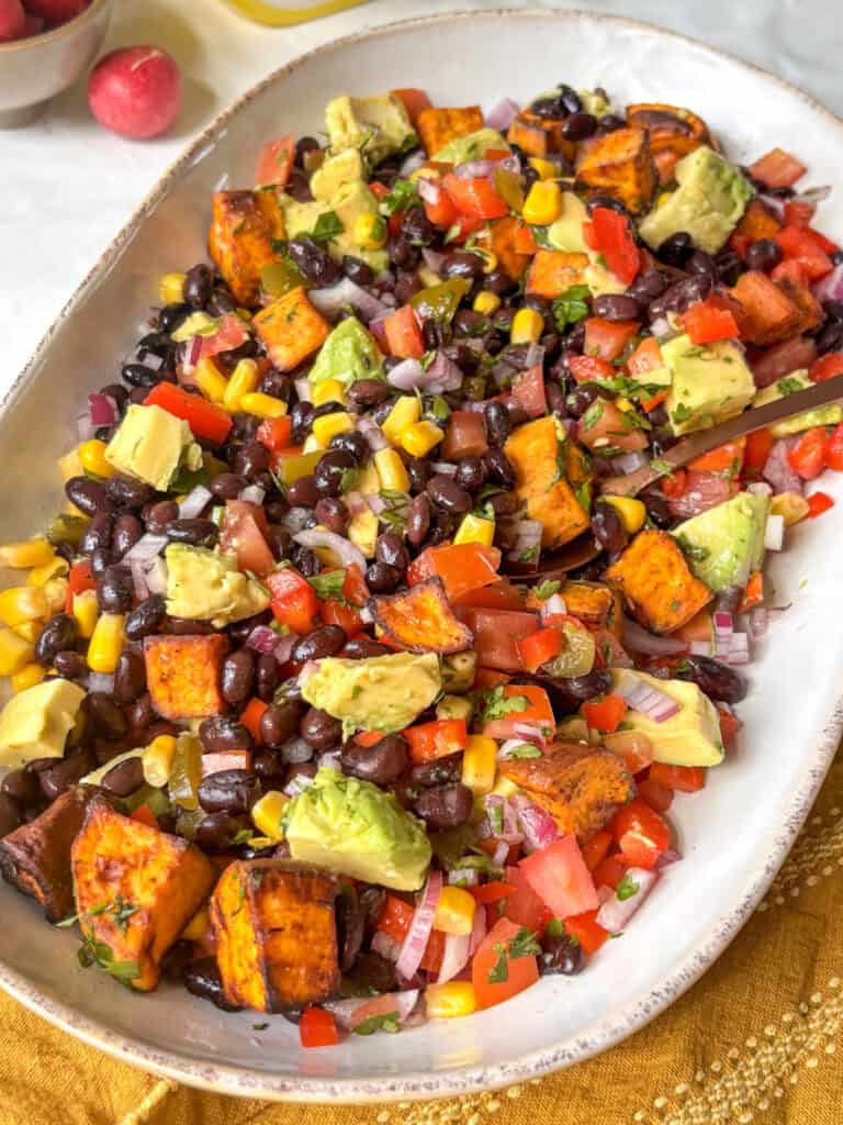 serving platter of high protein black bean salad with sweet potato, diced avocado, sweet corn, and tomatoes