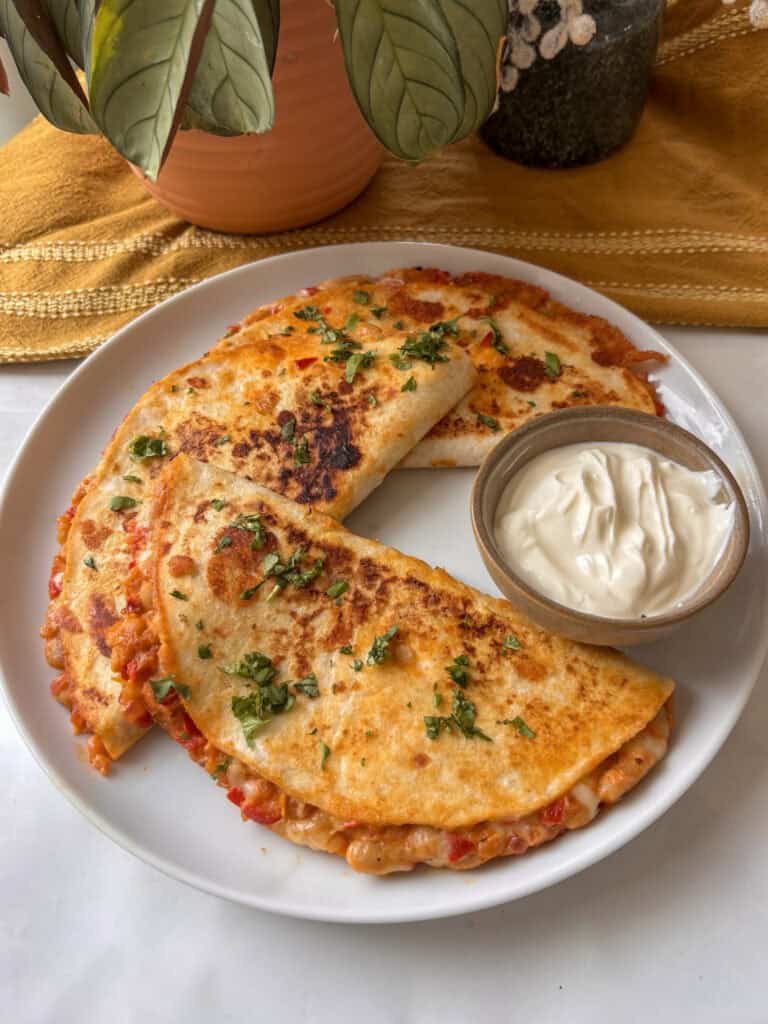 three buffalo white bean tacos on a plate with sour cream in a bowl