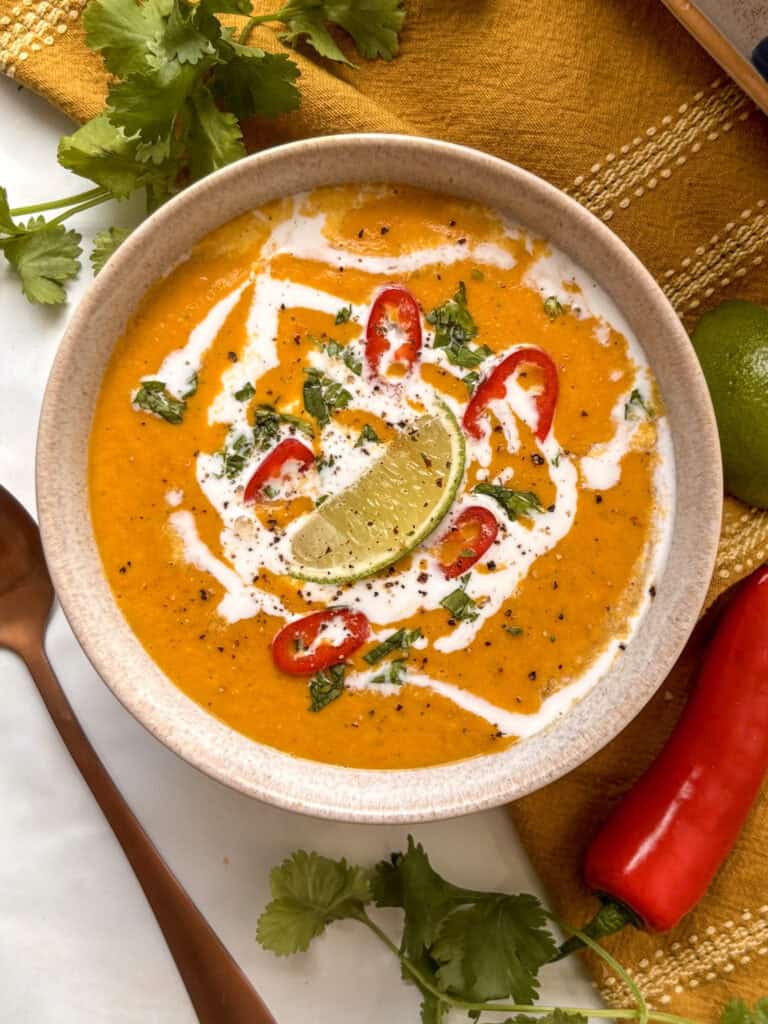 creamy coconut red curry soup topped with coocnut milk, red chili, lime, and fresh herbs
