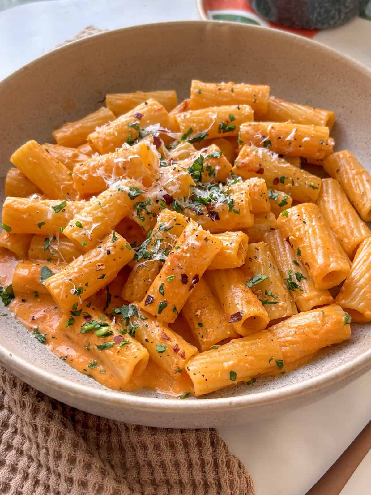 one bowl creamy tomato pasta with mascarpone cheese, topped with parsley and parmesan