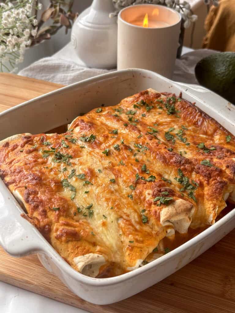 a casserole dish of cheesy lentil enchiladas topped with chopped cilantro