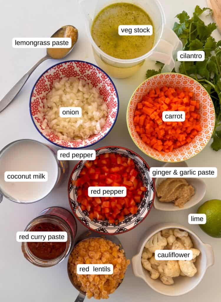 ingredients needed for coconut curry lentil soup: red lentils, onions, carrot, red pepper, garlic and ginger paste, lemongrass paste, veg stock, cilantro, coconut milk, lime, cauliflower, red curry paste