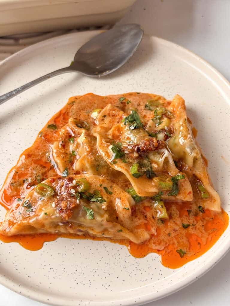 red curry dumpling bake topped with spring onions, cilantro, and chili crisp