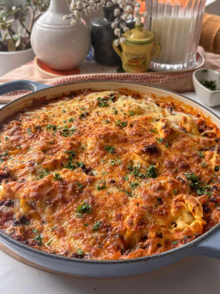 baked casserole pan of baked tortellini lasagna with a cheesy topping and fresh herbs